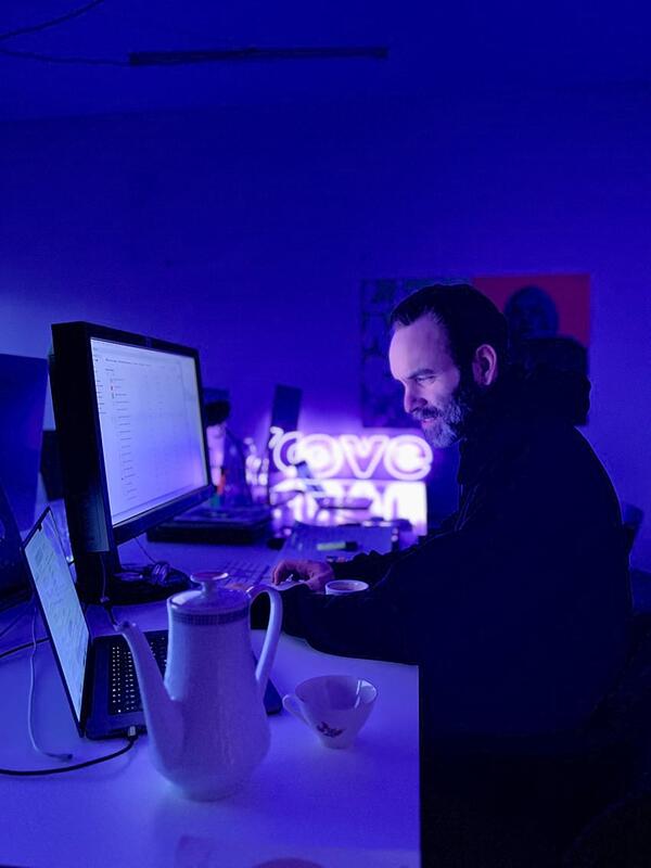 A man working on a computer in a room illuminated by blue light