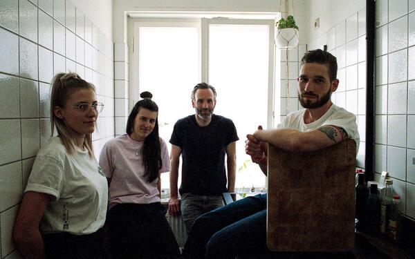 people sitting and standing in a small office kitchen